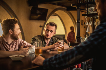 Fototapeta na wymiar Cheerful friends drinking draft beer in a pub