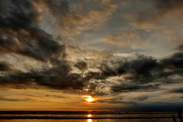 tourists while enjoying the sunset on Kuta beach, with an exciting atmosphere, the color of the sky is golden and the weather is sunny, so visitors are very comfortable to linger