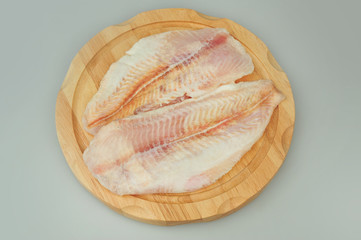Pangasius fillet meat on a board on gray isolated background