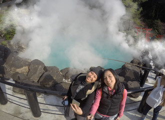 Two Asian tourist women take a photo at Hot spring (Hell) onsen, hot blue water The "sea hell" in Umi Jigoku at Beppu, Oita-shi, Kyushu, Japan. Shooting with superwide angle, action camera.