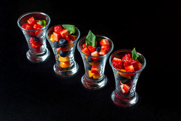 Four cups with sliced strawberries and blueberries.