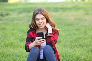 Happy teen using smart phone on the grass