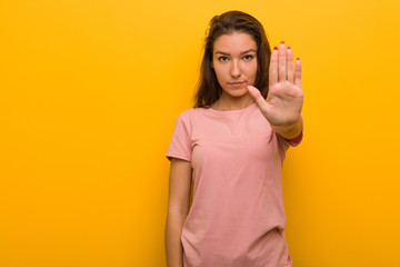Young european woman isolated over yellow background standing with outstretched hand showing stop sign, preventing you.