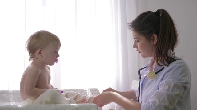 healthy childhood, professional family doctor female examines nice child boy in bright natural light close up in clinic in bright room