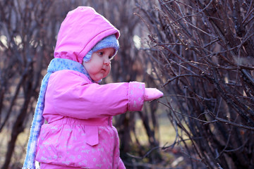 The one-year-old girl takes the first steps in the garden.