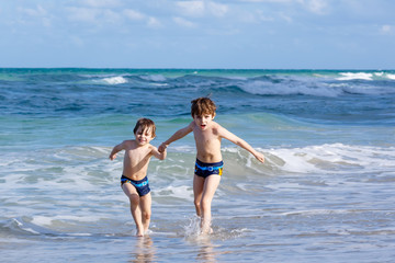 Naklejka premium Two kid boys running on ocean beach. Little children having fun