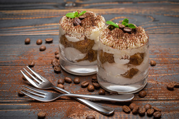 two portions Classic tiramisu dessert in a glass on wooden background