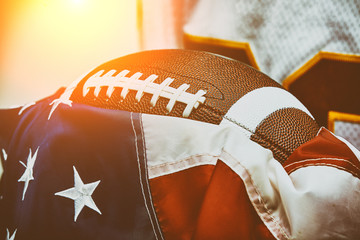 American football concept. The ball for American football lies on the flag of America against the backdrop of an American football player.