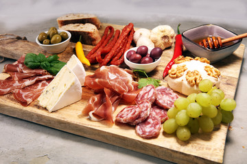 Cutting board with prosciutto, salami, cheese,bread and olives on dark stone background