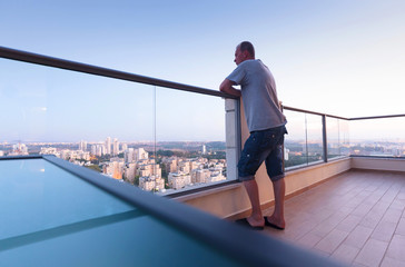  Man on the balcony look on evening city.