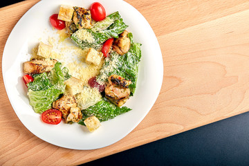 Caesar salad with chicken on wooden table
