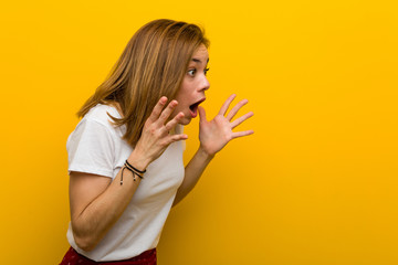 Young natural caucasian woman shouts loud, keeps eyes opened and hands tense.