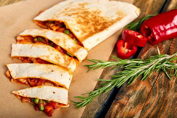 Mexican quesadilla with chicken, cheese and peppers on wooden table.