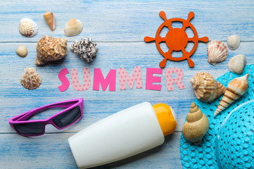 Inscription summer from paper of multi-colored letters and seashells and summer and sea accessories on a blue wooden table. Summer. relaxation. vacation. top view