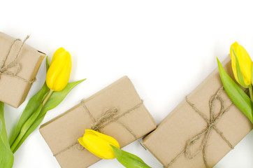 Gift boxes in craft paper with yellow tulips are on a white background