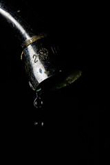 Faucet leaking water to black background. Macro detail of drop of water being wasted