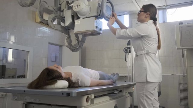 Woman doctor conducts Medical x-Ray Machine In Hospital Diagnostic Laboratory for girl. 4k