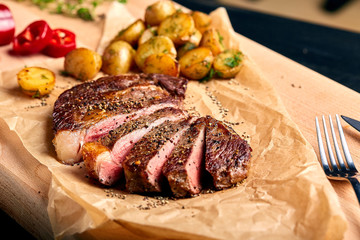 Tasty and fresh, very juicy Ribeye steak from marbled beef on a wooden table with baby potatoes