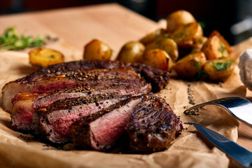 Tasty and fresh, very juicy Ribeye steak from marbled beef on a wooden table with baby potatoes