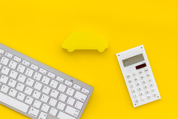 Car insurance concept with keyboard, car toy and calculator on yellow background top view