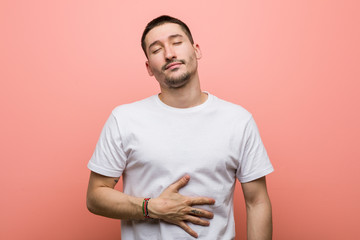 Young casual man touches tummy, smiles gently, eating and satisfaction concept.