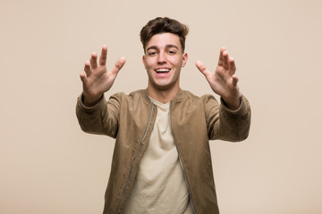 Fototapeta premium Young caucasian man wearing a brown jacket feels confident giving a hug to the camera.