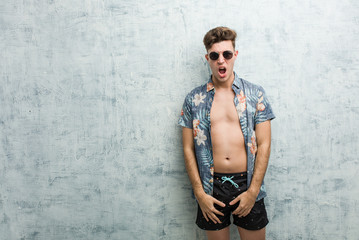 Fototapeta na wymiar Young caucasian man wearing a swimsuit screaming very angry and aggressive.