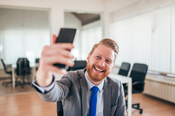 Happy businessman taking selfie at work.