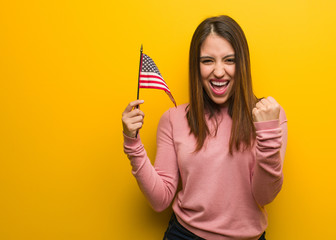 Young cute woman holding an united states flag surprised and shocked