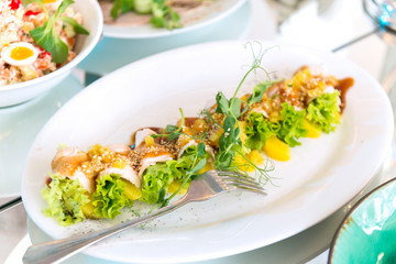 fish rolls with potatoes and greens, green salad leaves on a plate