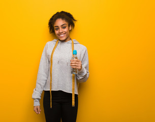 Young fitness black woman cheerful with a big smile.Holding a water bottle.