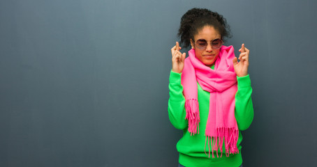 Young african american girl with blue eyes crossing fingers for having luck