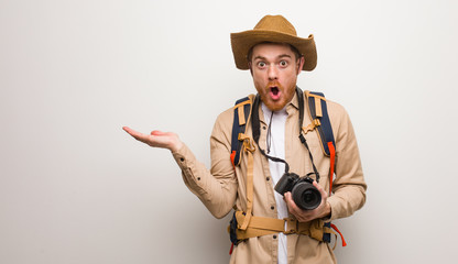 Young redhead explorer man holding something on palm hand. Holding a camera.