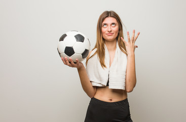 Young fitness russian woman very scared and afraid. Holding a soccer ball.