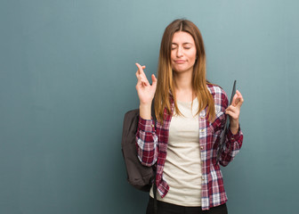 Young student russian woman crossing fingers for having luck
