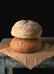 two loaves of baked round bread lay on brown paper