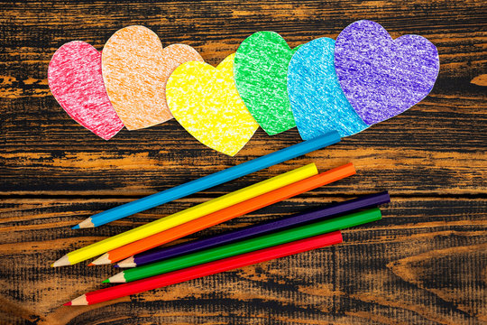 Hearts and pencils painted in LGBT colors. Located on wooden background.