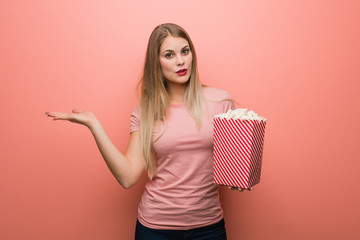 Young pretty russian girl holding something on palm hand. She is holding popcorns.