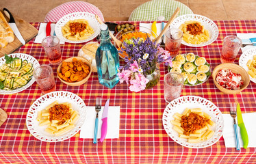 Italian style food and drink. Table ready for lunch waiting for the five people. Family or friends. Colors and joy