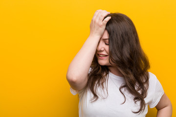 Young curvy plus size woman forgetting something, slapping forehead with palm and closing eyes.