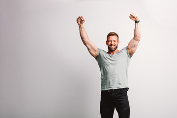 Handsome fit man raising his arms in winning gesture.