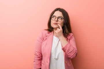 Young plus size business caucasian woman looking sideways with doubtful and skeptical expression.