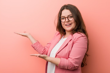 Young plus size business caucasian woman excited holding a copy space on palm.