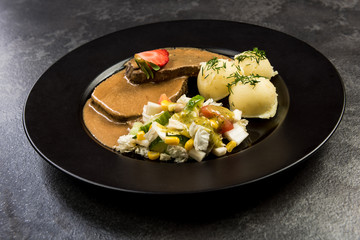 Pork meat with sauce, potatoes and salad, restaurant serving portion