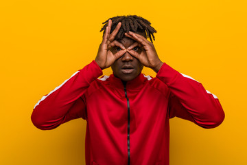 Young fitness black man showing okay sign over eyes