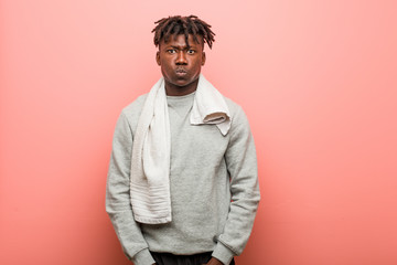 Young fitness african black man blows cheeks, has tired expression. Facial expression concept.