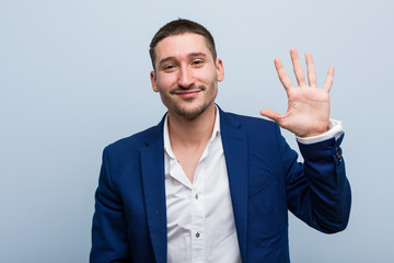Young business caucasian man smiling cheerful showing number five with fingers.