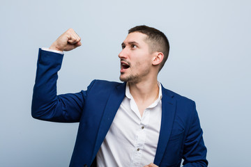 Young business caucasian man raising fist after a victory, winner concept.