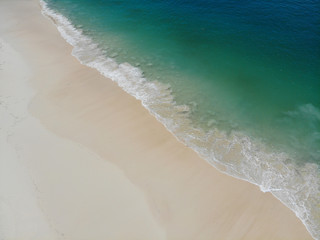 Beach scene in summer with waves sea clear and beautiful top view by drone