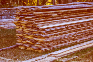 Processed lumber on the background of the autumn landscape.